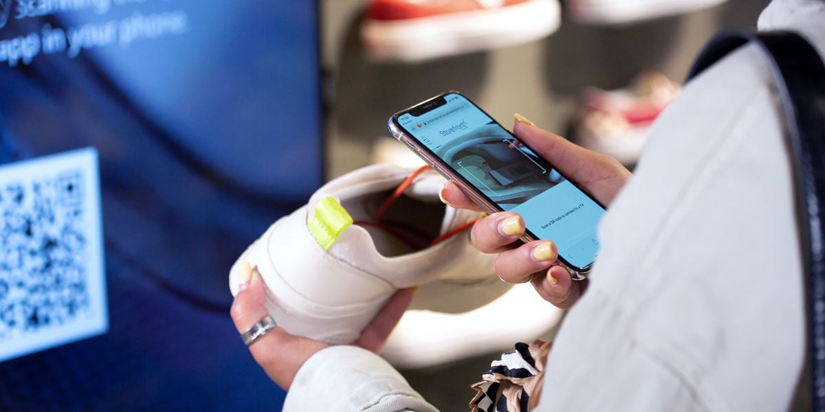 Någon som scannar en produkt i en butik med sin mobil